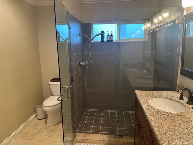 a bathroom with a granite countertop sink a toilet a mirror and shower