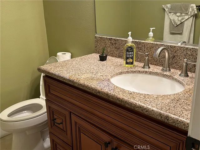 a bathroom with a granite countertop sink a toilet and a mirror