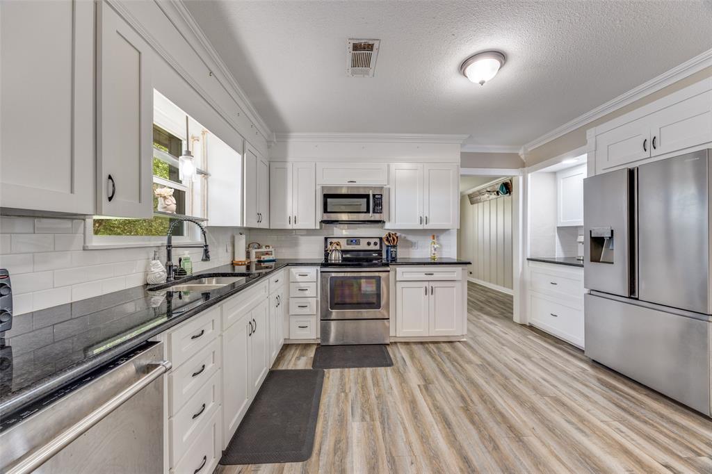 a kitchen with granite countertop white cabinets and stainless steel appliances