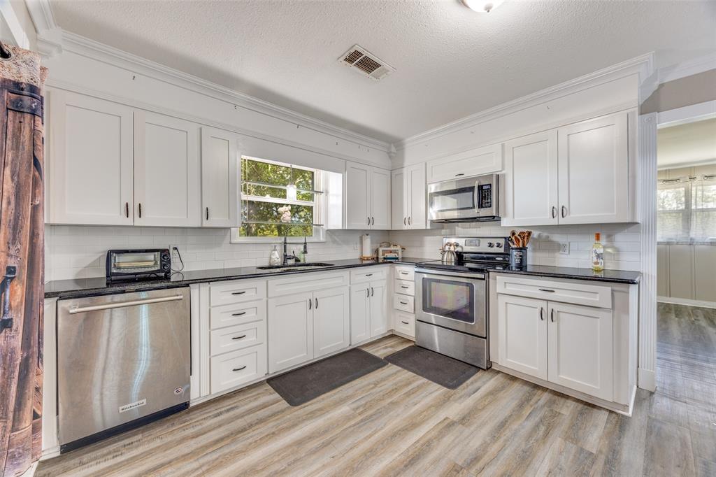 9591 Dripping Spring Road Denison, TX 75021 - Photo 6 of 23 a kitchen with stainless steel appliances granite countertop white cabinets sink and window