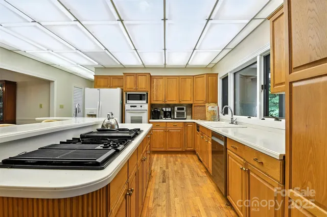 a kitchen with stainless steel appliances a stove a sink dishwasher and white cabinets with wooden floor