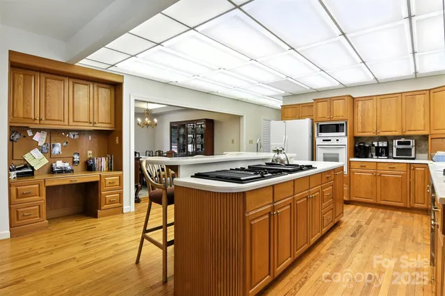 a kitchen with stainless steel appliances granite countertop a stove a sink dishwasher and a refrigerator with wooden floor