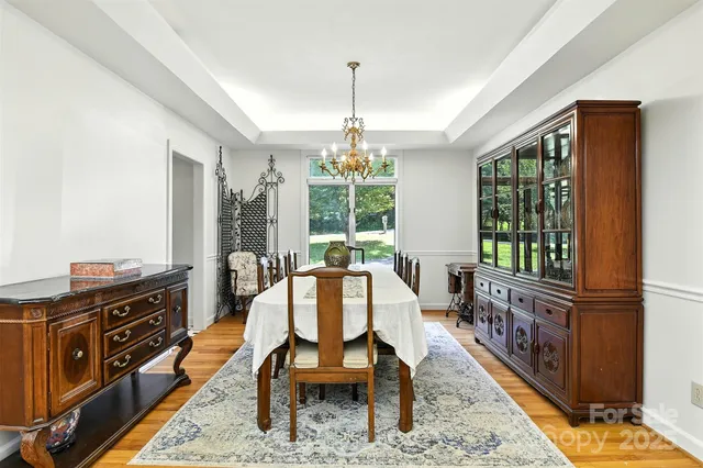 a dining room with wooden floor a chandelier a wooden table and chairs