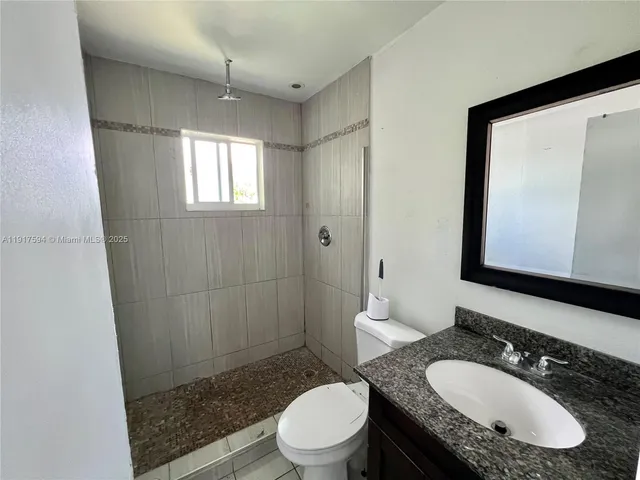 a bathroom with a granite countertop sink toilet a mirror and shower