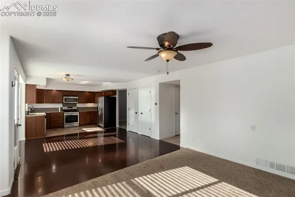 a kitchen with stainless steel appliances granite countertop a stove top oven a sink dishwasher a dining table and chairs with wooden floor