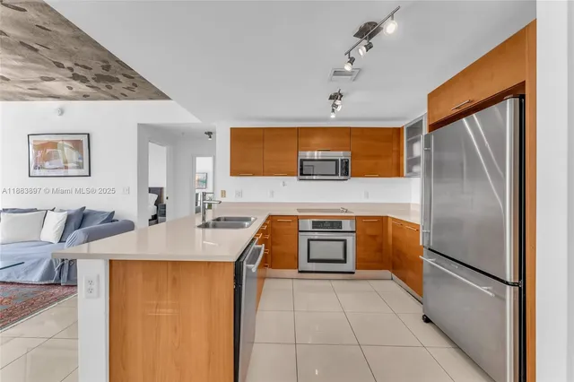 a kitchen with stainless steel appliances granite countertop a refrigerator a stove top oven and a sink