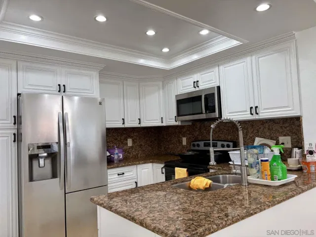 a kitchen with stainless steel appliances granite countertop a refrigerator a stove and a sink