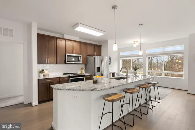 a kitchen with sink a stove a refrigerator and chairs