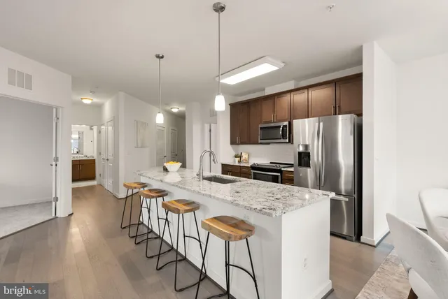 a kitchen with stainless steel appliances kitchen island granite countertop a refrigerator a stove a sink a oven with a dining table and chairs