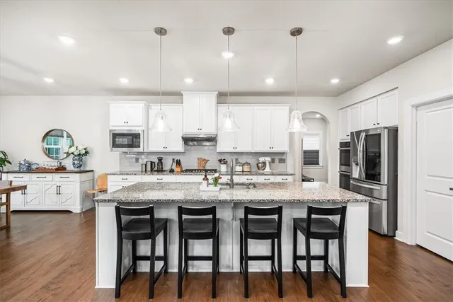 a kitchen with stainless steel appliances granite countertop a sink stove refrigerator and cabinets