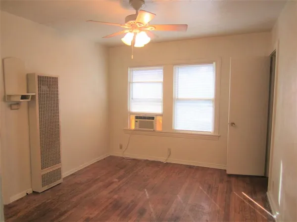 an empty room with a window and a fan