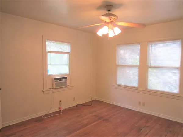 an empty room with wooden floor chandelier and windows