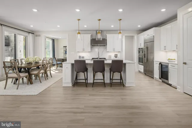 a view of a dining room and livingroom with furniture wooden floor a rug a fireplace and windows