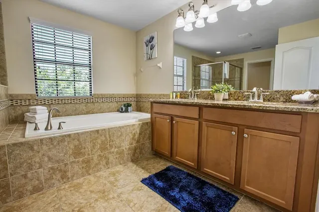 a spacious bathroom with a granite countertop sink a large mirror a bathtub and window
