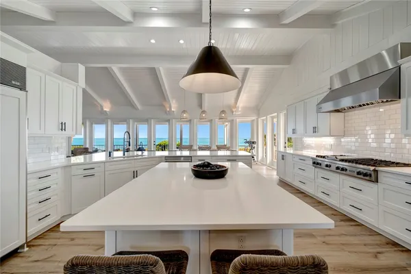 a kitchen with stainless steel appliances a stove a sink a dining table and chairs