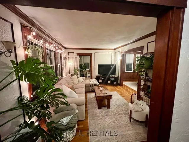 a living room with furniture potted plant and a large window