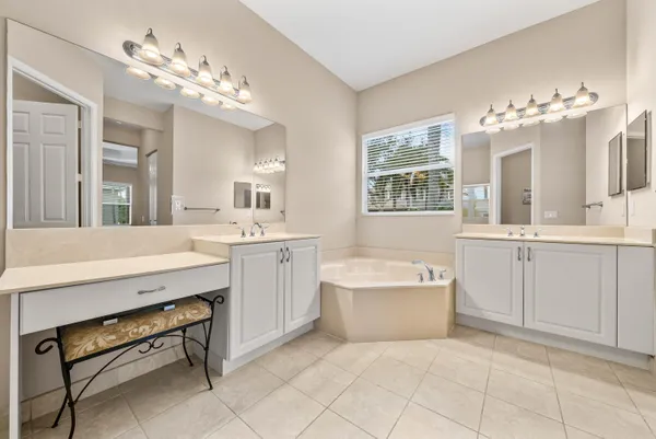a spacious bathroom with a double vanity sink a mirror a bathtub and a window