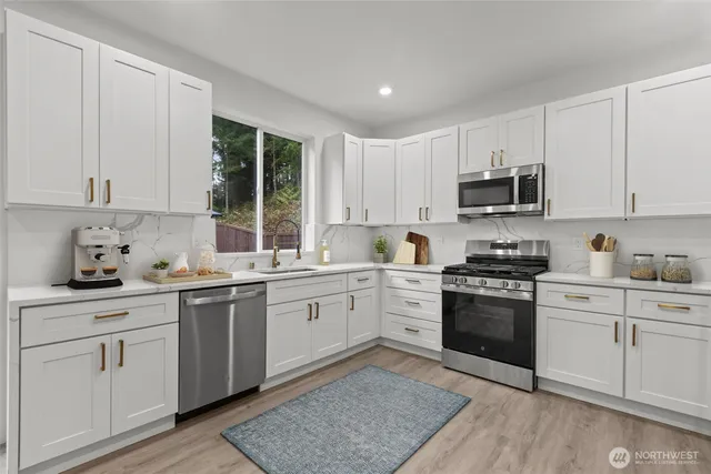 a kitchen with cabinets stainless steel appliances a sink and a window