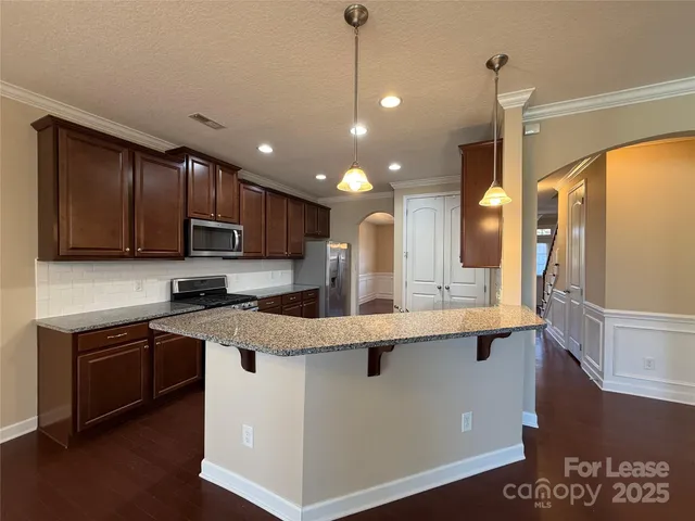 a kitchen with stainless steel appliances granite countertop wooden cabinets and a stove top oven