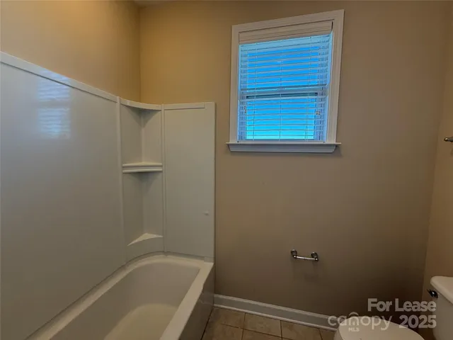 an empty room with ceiling fan and windows
