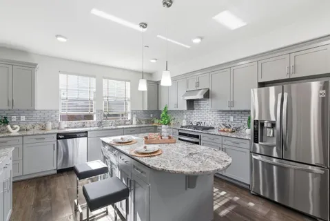 a kitchen with a refrigerator a stove a sink and white cabinets with wooden floor