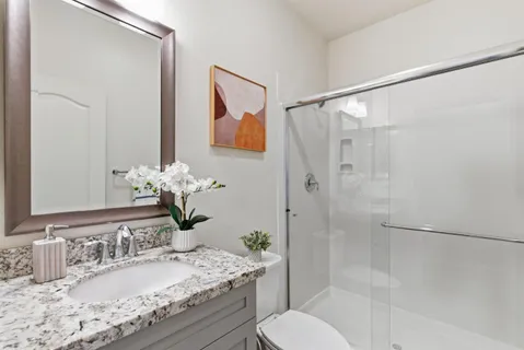 a bathroom with a granite countertop sink toilet and shower