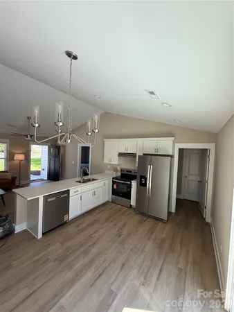 a kitchen with stainless steel appliances kitchen island wooden floors and white cabinets