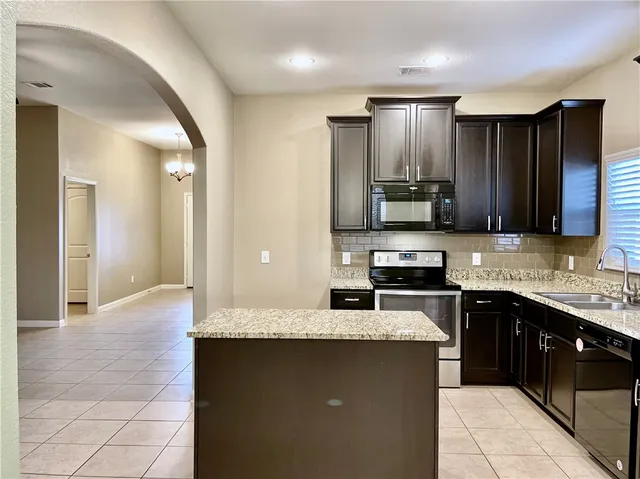 a kitchen with granite countertop a stove microwave and sink