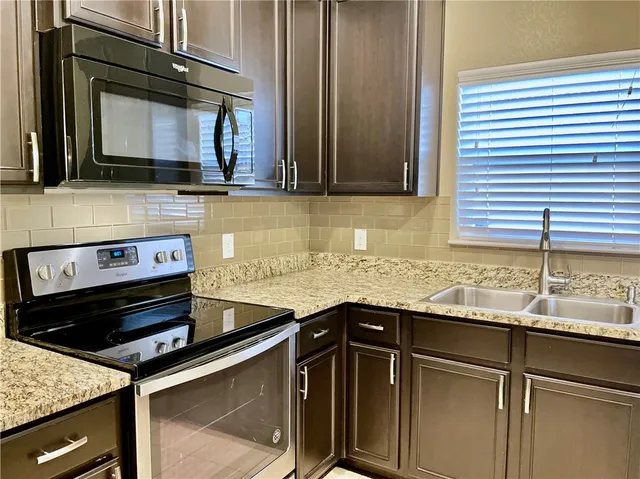 a kitchen with stainless steel appliances granite countertop a sink stove and microwave