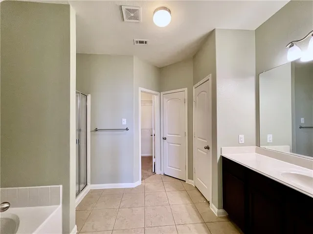 a spacious bathroom with a tub sink shower and mirror