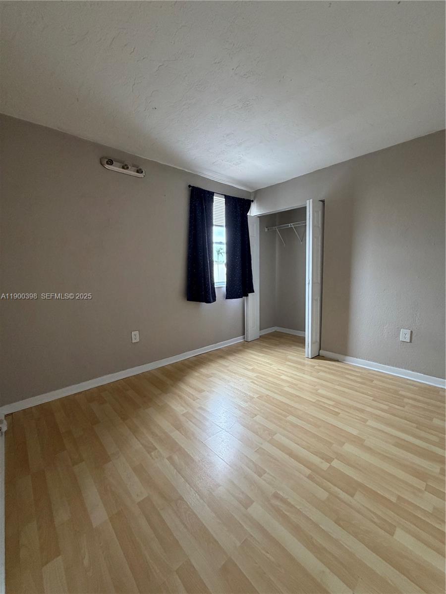 4515 Southwest 68th Ct Circle, Unit 1 Miami, FL 33155 - Photo 12 of 16 a view of an empty room with window and wooden floor