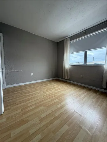 an empty room with wooden floor and a bathroom