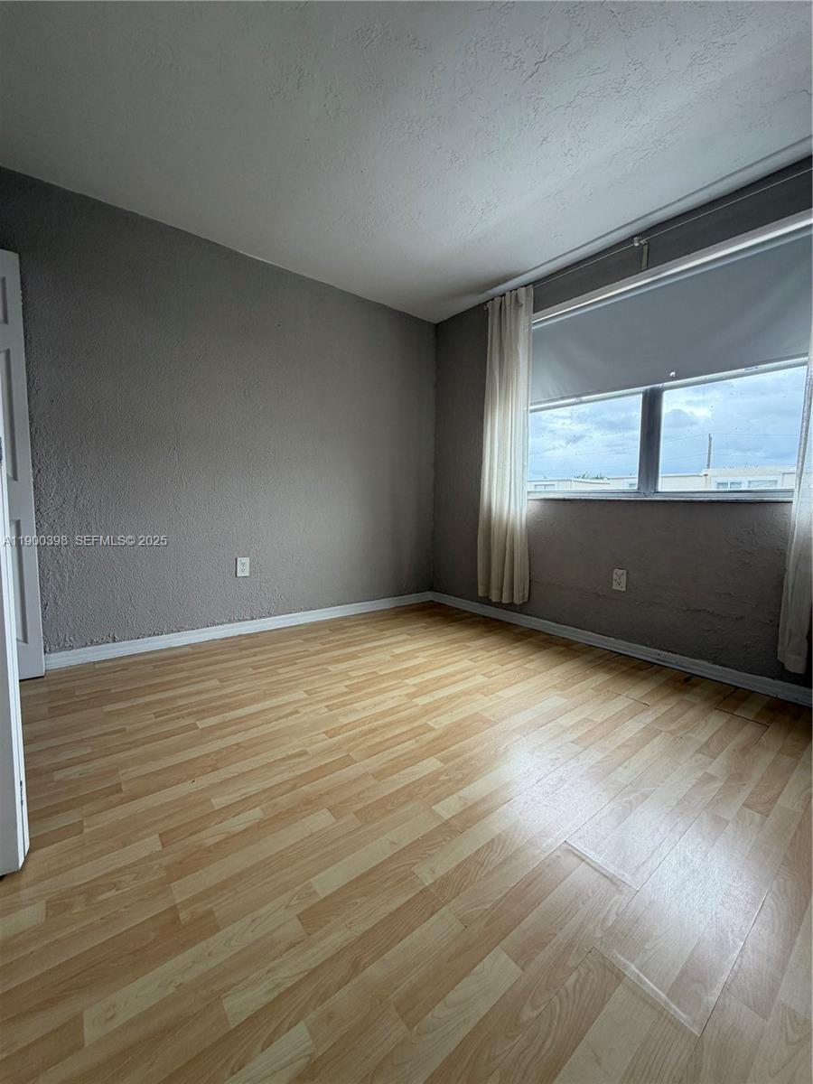 4515 Southwest 68th Ct Circle, Unit 1 Miami, FL 33155 - Photo 13 of 16 a view of an empty room with wooden floor and a window