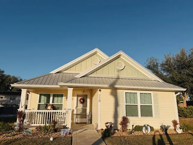 a view of a brick house with large windows and a small yard
