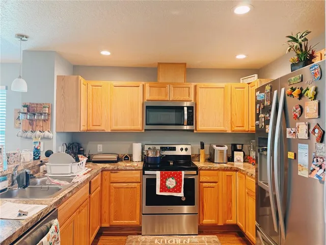 a kitchen with stainless steel appliances granite countertop a refrigerator stove top oven a sink and dishwasher