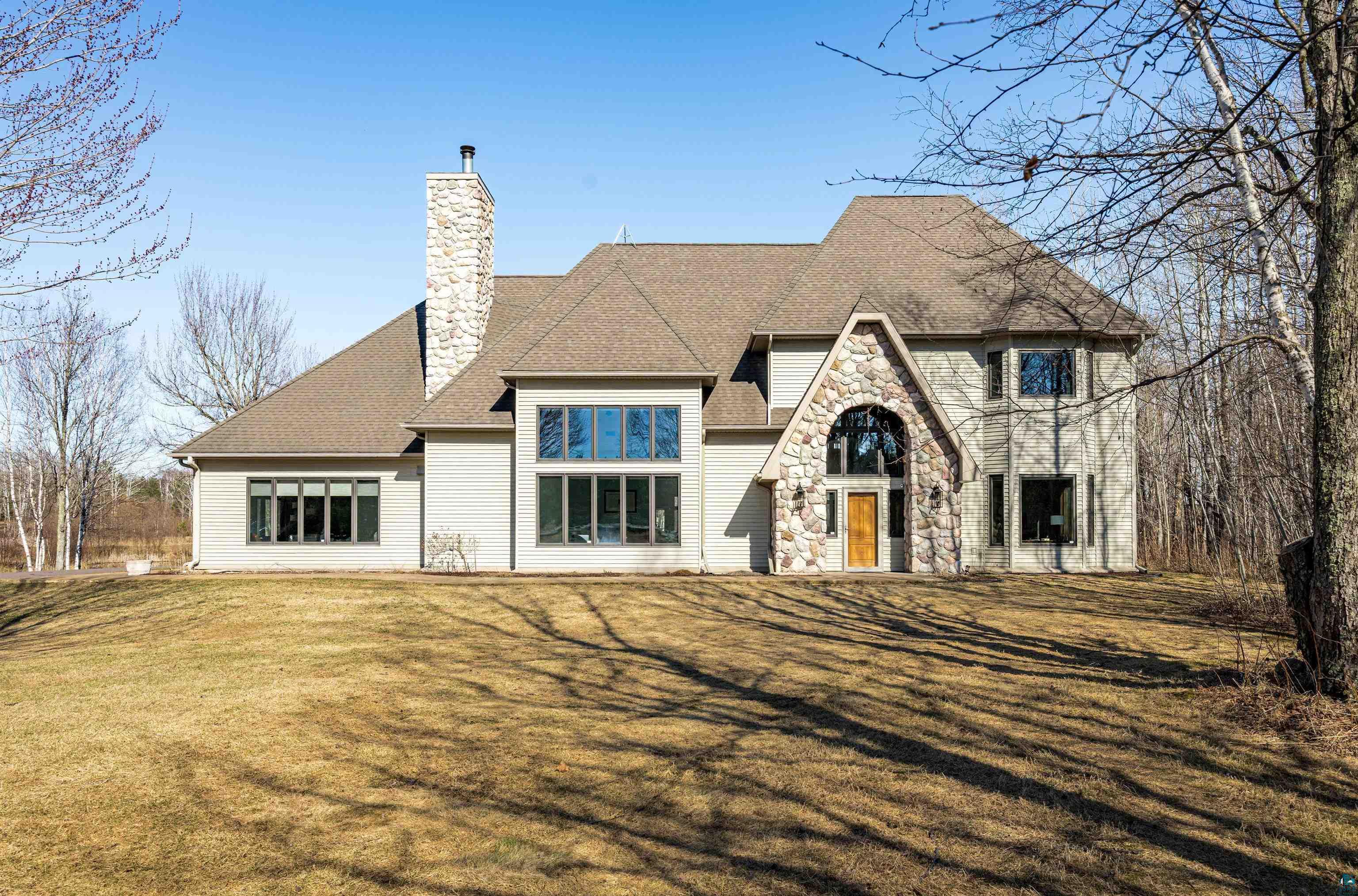 Modern traditional residence featuring a prominent stone facade entrance with an arched window and a solid wood door