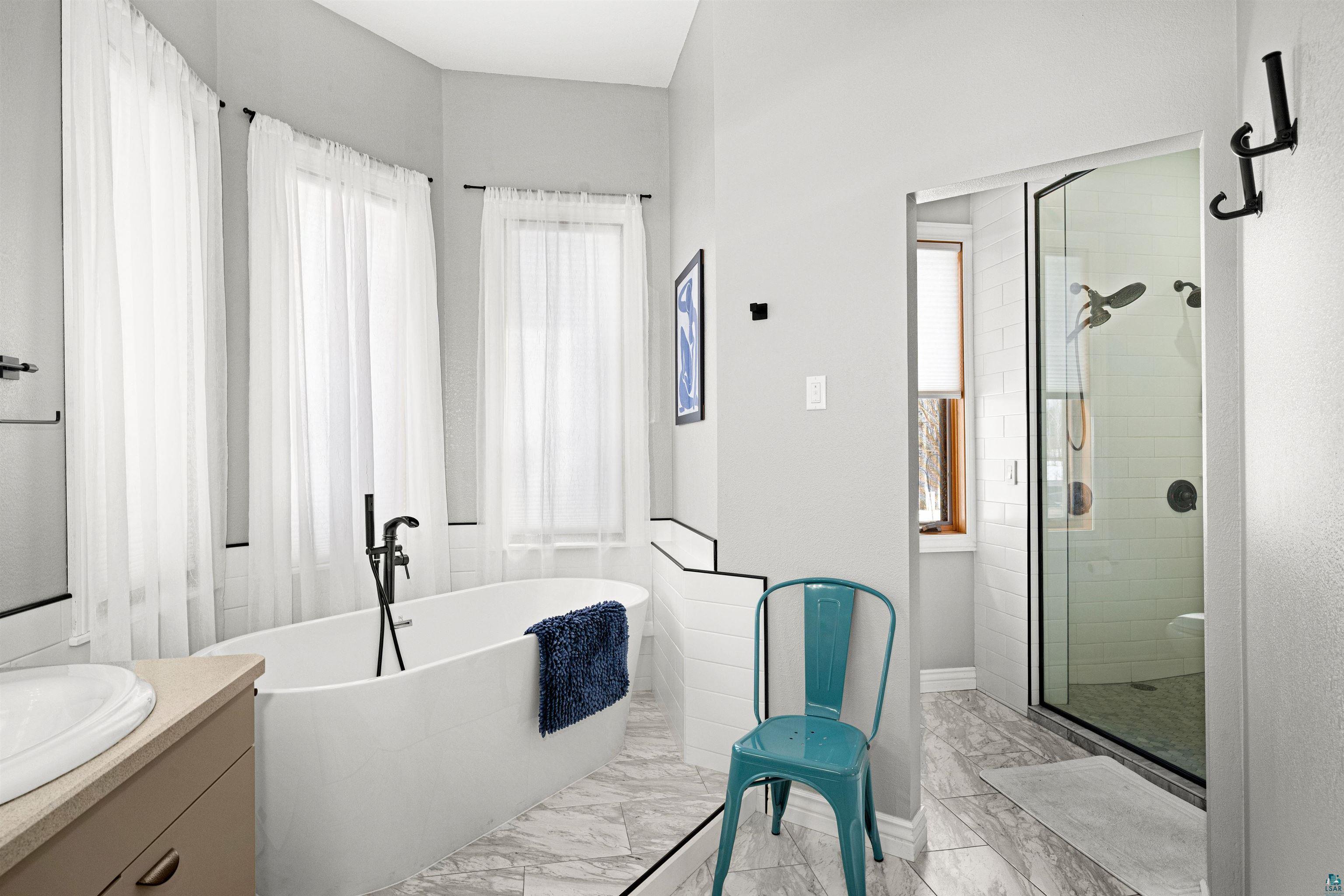 390 Crosby Road Cloquet, MN 55720 - Photo 21 of 42 Full bath with vanity, a stall shower, a soaking tub, and light marble finish flooring