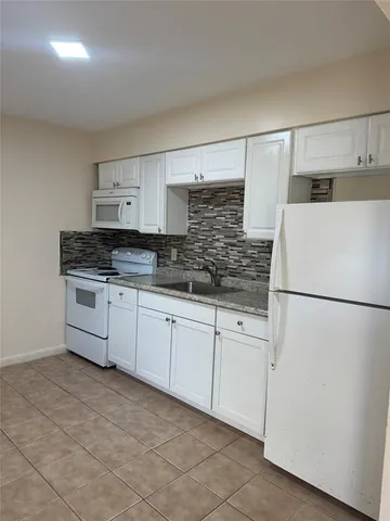 a kitchen with stainless steel appliances granite countertop a refrigerator sink and white cabinets
