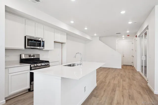 a kitchen with stainless steel appliances a stove a sink a microwave a refrigerator and cabinets