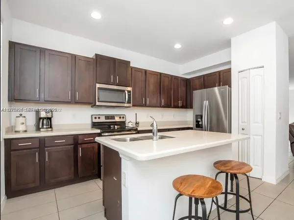 a kitchen with stainless steel appliances granite countertop a stove a sink a refrigerator a dining table and chairs