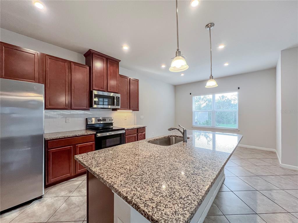 8511 Rain Lily Crossing Parrish, FL 34219 - Photo 6 of 34 a kitchen with stainless steel appliances granite countertop wooden cabinets a refrigerator and a sink
