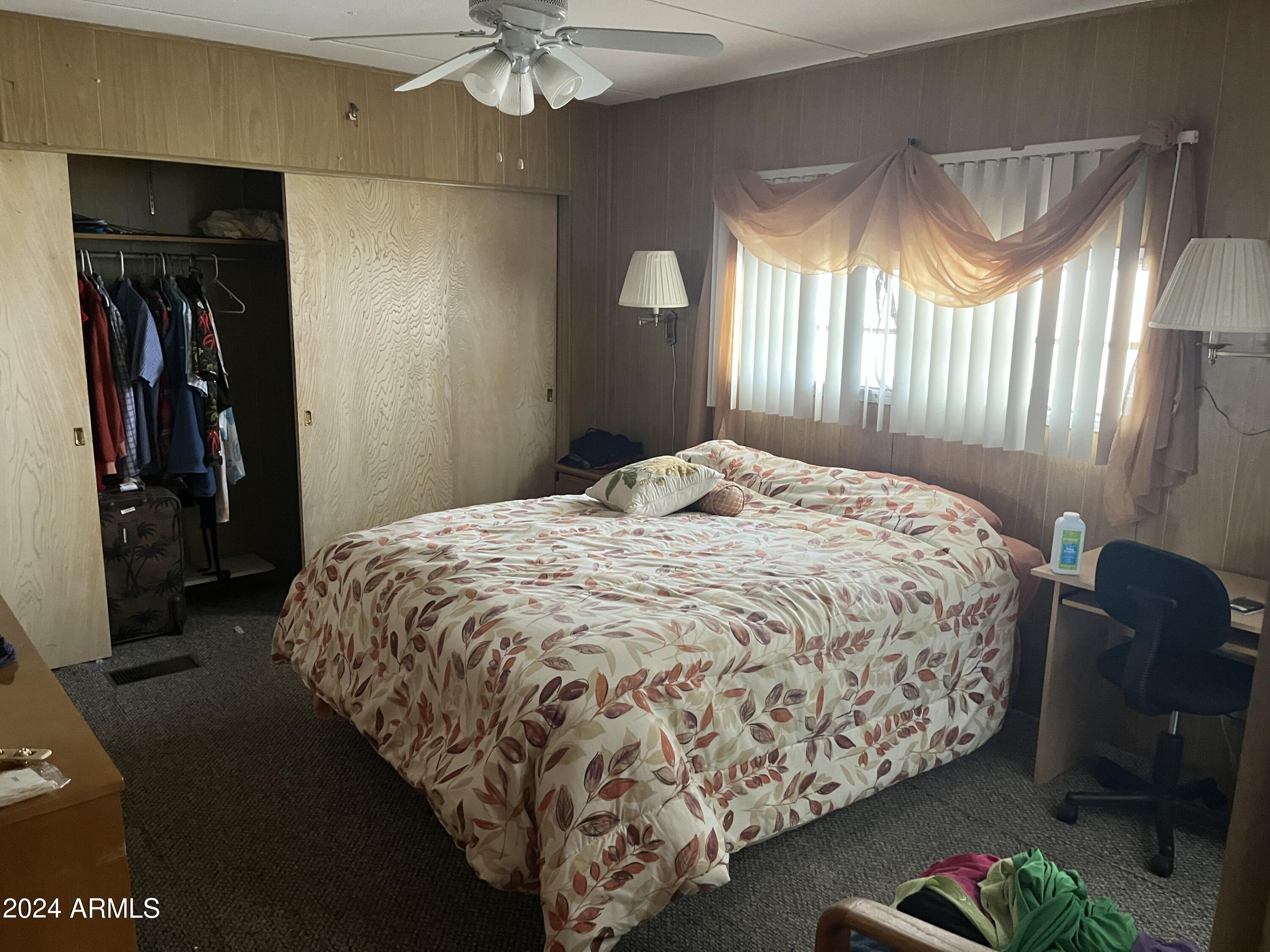 2460 East Main Street, Unit F2 Mesa, AZ 85213 - Photo 10 of 17 a bed sitting in a bedroom next to a window and a chandelier