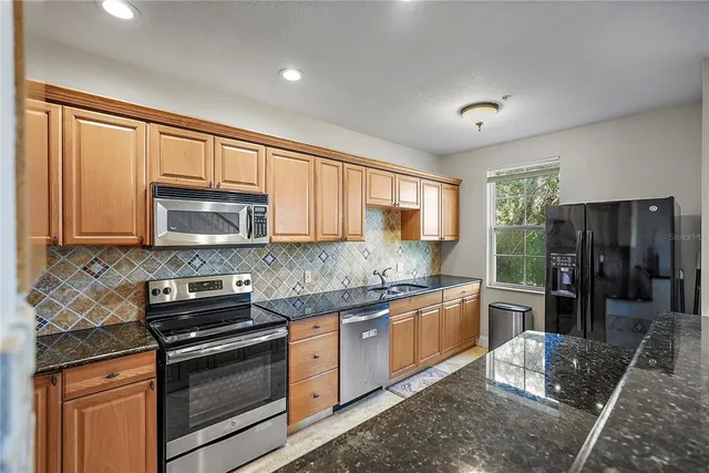 a kitchen with stainless steel appliances granite countertop a stove sink and cabinets