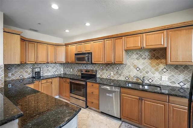 a kitchen with granite countertop sink stainless steel appliances and window