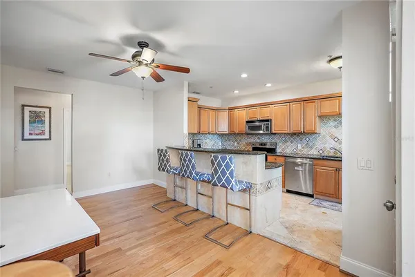 a kitchen with stainless steel appliances granite countertop a stove top oven a sink dishwasher and white cabinets with wooden floor