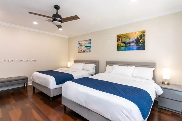 a bedroom with two beds and a ceiling fan