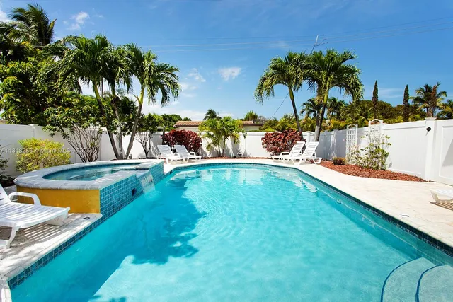 a view of a swimming pool with a lawn chairs under palm trees