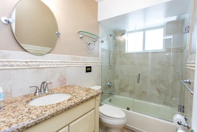 a bathroom with a granite countertop sink mirror toilet and bathtub
