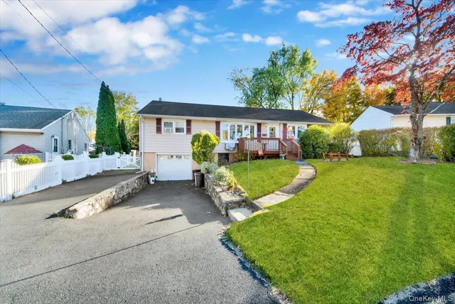 a view of a house with a big yard and large tree