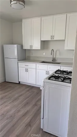 a white kitchen with granite countertop stainless steel appliances
